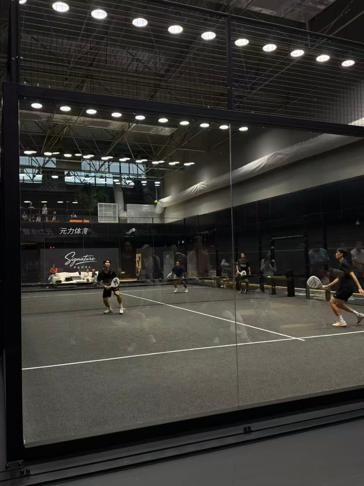 Signature Padel 北京的玻璃板式网球场上，四位球友正在对打